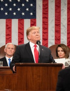 President Donald Trump with Vice President Mike Pence and Speaker of the House Nancy Pelosi in the background.