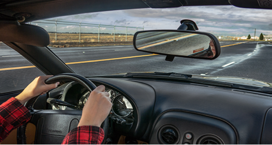 A photograph shows a person driving a car.