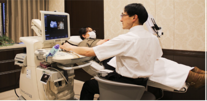 A technician uses ultrasound equipment to examine a pregnant woman's belly.